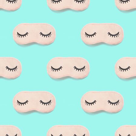 Seamless pattern from pink sleep mask with closed eyes embroidered on it with eyelashes on turquoise background. Photographic collage. Top view, flat lay. Accessories for girls and young women.の写真素材