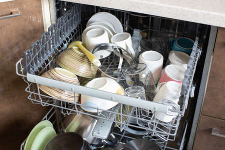 Clean dishes in dishwasher. Freshly washed dishes, plates, cups, jars, mugs, cutlery, pots. Concept of hygiene, household, home care, water saving, technologies and helpers in everyday life.の写真素材