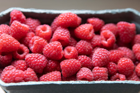 Close-up of a lot of raspberries in a shop filling container in day light. Concept for organic berries, vegetarianism, healthy eating, natural vitamins. Soft selective focus. Horizontal.の写真素材