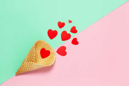 Festive spring flat lay. Red hearts in waffle cone on pastel pink and turquoise background, close-up, copy space. March 8, February 14, St. Valentine's, Mother's, Women's day celebration concept.の写真素材