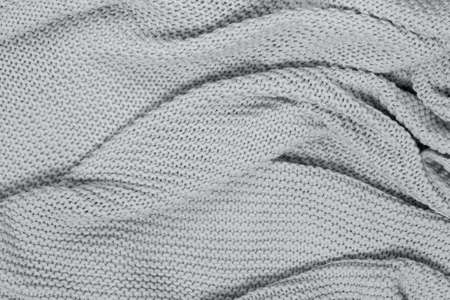 Textured surface of knitted cotton wave plaid, top view. Soft gray wool backdrop. Seasonal cosiness...