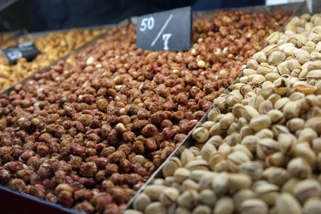 Lots of nuts on the counter at the fair, market, salted caramel almonds, fried pistachios. Concept for a healthy outdoor snack. Side view, place for text, copy space.の写真素材