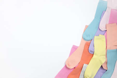 Multicolored children's socks without pattern, laid out in corner of frame, on white background with copy space, flatly, minimal style. Concept children's clothing, housekeeping.の写真素材