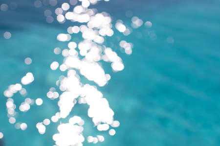 View of blurry surface of turquoise water with glare in swimming pool, sea, lake, or ocean, summer mood background. Concept rest, travel, wellness, spa procedures, season of vacations, sport.の写真素材