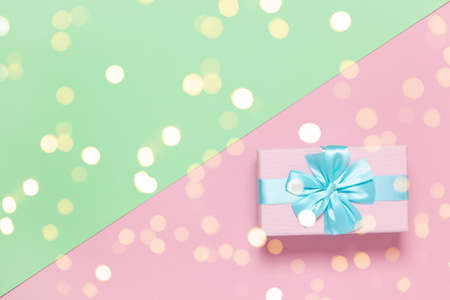 Pink gift box with blue bow on pastel two-color background pink and green, copy space, flat lay....