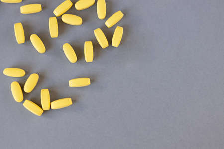 Yellow long vitamins or pills on a gray background, close-up, mock up, copy space. Nutritional...