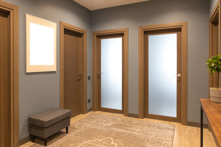 Modern entrance hallway in neutral shades of brown and gray. tones. On the wall there is a photo frame with a mockup. The concept is fashionable interior design, the use of natural materials.の写真素材