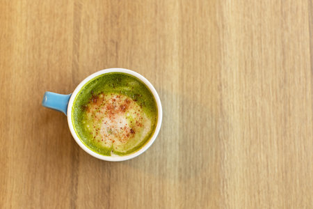 Blue cup with green tea matcha latte, with freeze-dried strawberries on wooden table, copy space. Healthy nutrition concept, drinks with vegetable or cow's milk, vegan beverages. Place for text.の写真素材