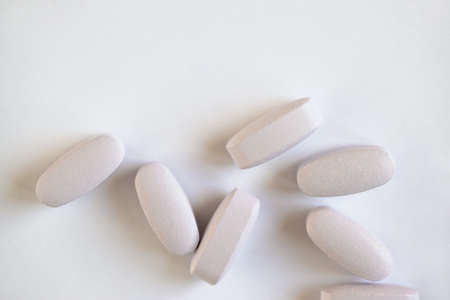 White or light gray long vitamins or pills on white background, macro, close-up, copy space, flatly. Nutritional supplements concept, health, vitamins, monochrome minimal style. Horizontal.の写真素材