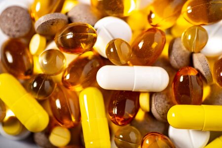 Pile of brown and yellow golden colourful medical pills spillt. Prescription tablets background. Medicine science and treatment concept. Pharmacy illustrationの写真素材