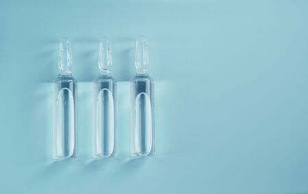 Row of three glass transparent ampules with medication liquid. Prescription solution lying isolated...