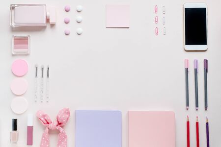Flat lay top view neatly layed isolated light pink background soft lilac colour pencils highliters stickers clips cell mobile phone perfume cosmetics head band sweets women girl concept text spaceの写真素材