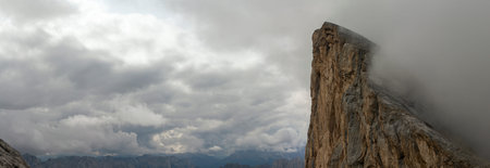 Vertical limestone wall towers above layered alpine ridges in Dolomites mountains, upper edge fading...