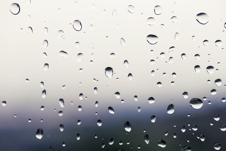 Glass with water drops in a rainy day, background blurredの写真素材