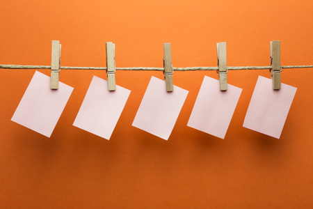 Post it notes hanging on a rope with clothespins, orange backgroundの写真素材
