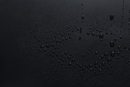 Closeup of black raindrops on a dark surface, abstract backgroundの写真素材