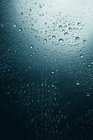 Bubbles of water on a shaded surface, blue backgroundの写真素材