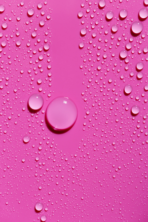 Drops of water on a fuchsia color surface, abstract backgroundの写真素材