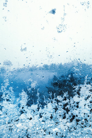 Snow and ice on the window glass, natural backgroundの写真素材