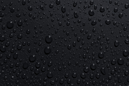 Closeup of black raindrops on a dark surface, abstract backgroundの写真素材