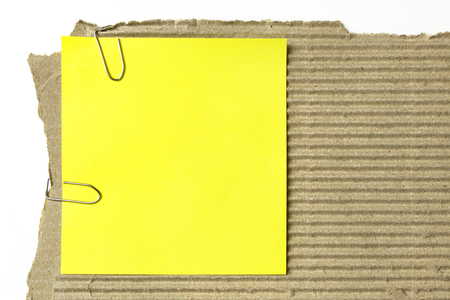Yellow sticky note on piece of cardboardの写真素材