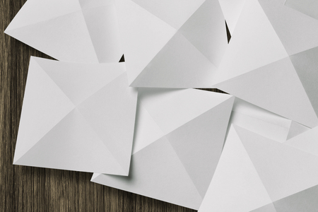Collection of white cards folded in pyramidal shapes; isolated on wooden boardの写真素材