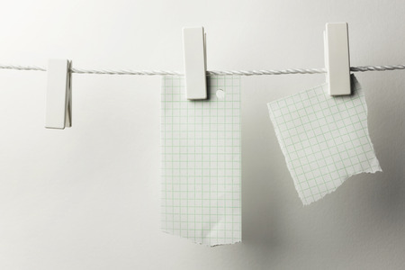 Pieces of note paper hanging with clothespins, isolated on whiteの写真素材