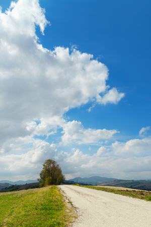 Landscape view from a white country road, blue sky with cloudsの写真素材