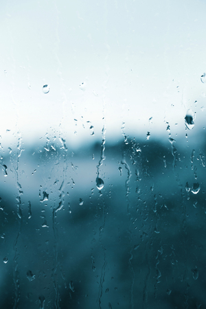 Raindrops on the glass, blurry landscape on backgroundの写真素材