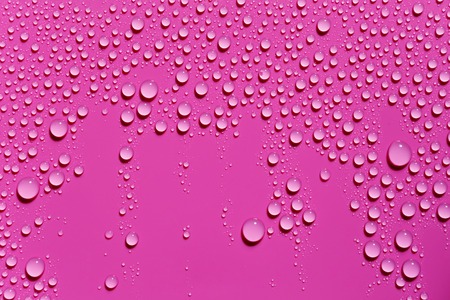 Drops of water on a fuchsia color surface, abstract backgroundの写真素材