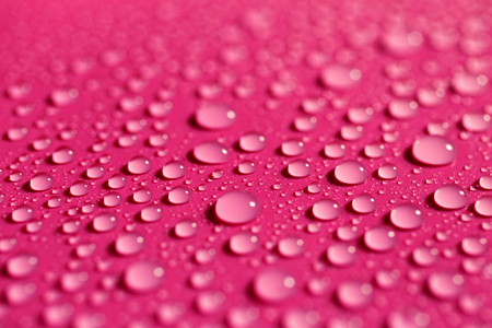 Drops of water on a fuchsia color surface, abstract backgroundの写真素材