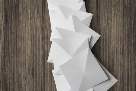 Collection of white cards folded in pyramidal shapes; isolated on wooden boardの写真素材