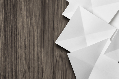 White cards folded in pyramidal shapes; isolated on wooden boardの写真素材