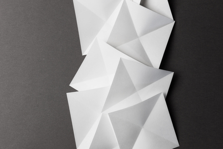 Overlapping geometric shapes of white paper; isolated on grey backgroundの写真素材