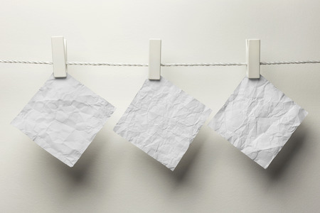 Crumpled note paper hanging with clothespins,isolated on whiteの写真素材
