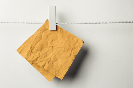 Crumpled note paper hanging with clothespin,isolated on whiteの写真素材