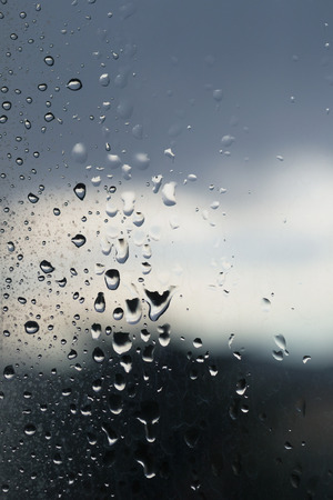 Dark raindrops dark on the glass, bad weather from the windowの写真素材