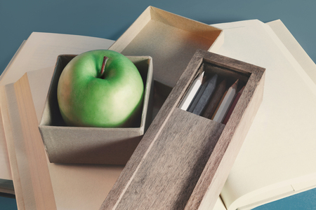 Green apple in a box, open books on backgroundの写真素材