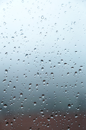 Glass of a window with raindrops, background blurredの写真素材