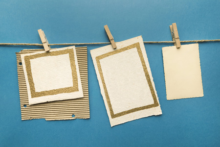Old cards hanging with wooden clothespins, blue backgroundの写真素材