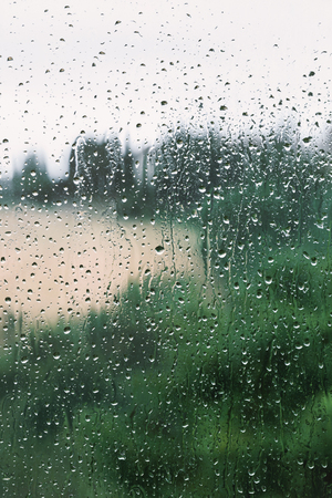Water drops on window in a rainy day, blurry view on backgroundの写真素材