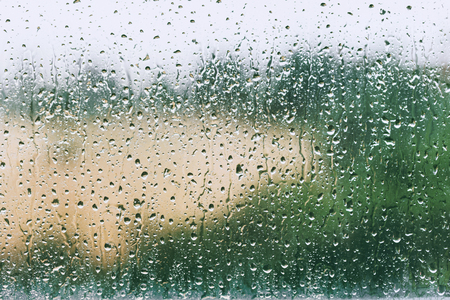 Water drops on window in a rainy day, blurry view on backgroundの写真素材