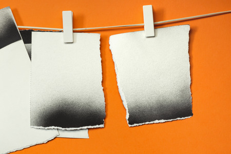 Old cards torn hung with the clothespins, orange backgroundの写真素材
