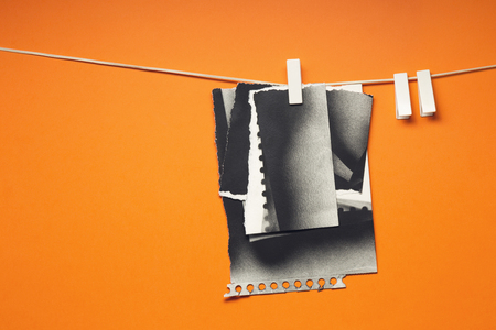 Old cards torn hung with the clothespins, orange backgroundの写真素材