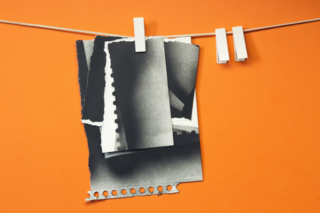 Old cards torn hung with the clothespins, orange backgroundの写真素材