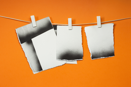 Old cards torn hung with the clothespins, orange backgroundの写真素材