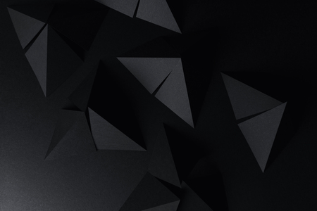 Black triangular shapes of paper on dark backgroundの写真素材