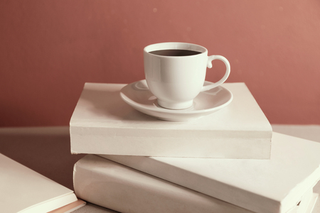 Cup of coffee over the stack of closed books, red wall backgroundの写真素材