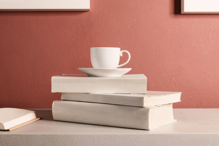 Cup of coffee over the stack of closed books, red wall backgroundの写真素材
