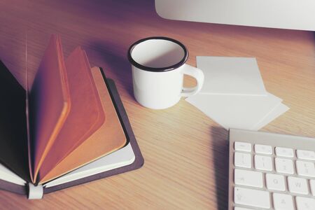 Office desk table with supplies. Cup, note book open and keyboardの写真素材